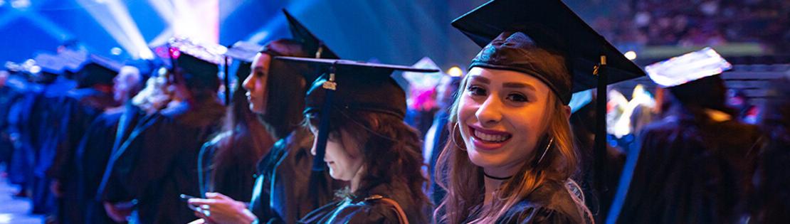 Smiling female student in cap and gown at PCC graduation